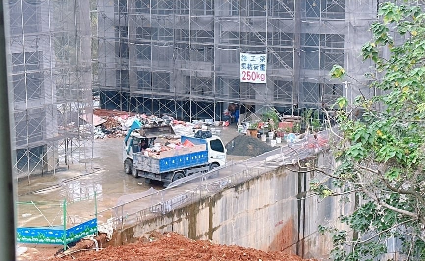 桃園市龜山區建築工地,2月25日一山貓抓斗車將廢棄物鏟入車斗。讀者提供