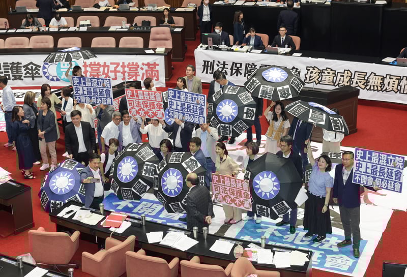 立法院院會表決通過再延會至8月31日,民進黨立委手舉標語,質疑藍白延會是為將司法保護傘撐好撐滿。中央社