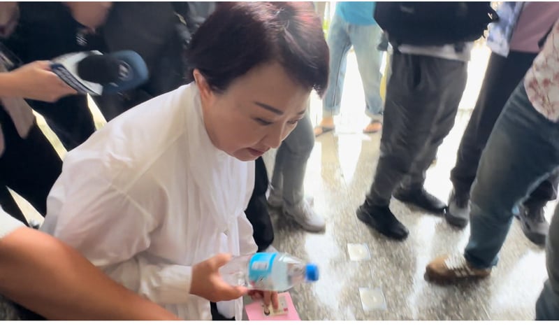 台中市長盧秀燕上午前往投開票所投票，有選務人員的水瓶被碰倒在地，盧秀燕彎腰幫忙撿起。中央社