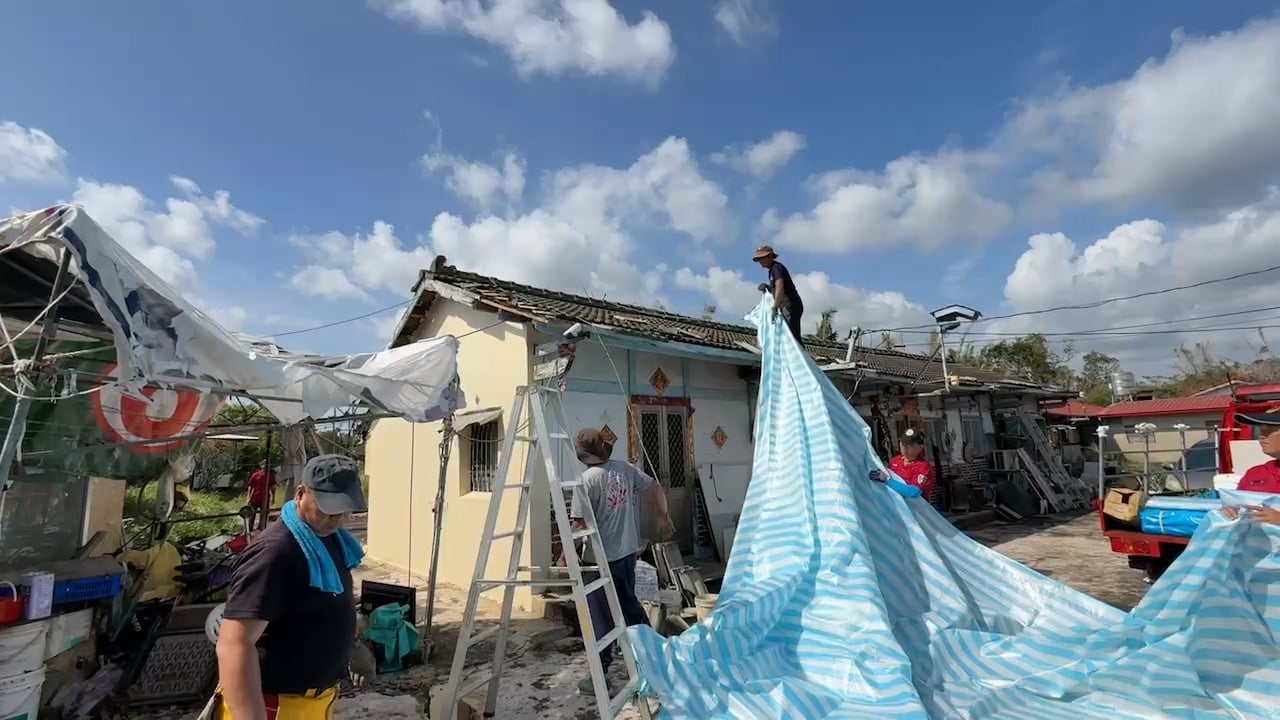 義消團體趁好天氣時在破損屋頂上覆蓋帆布。辛啓松攝