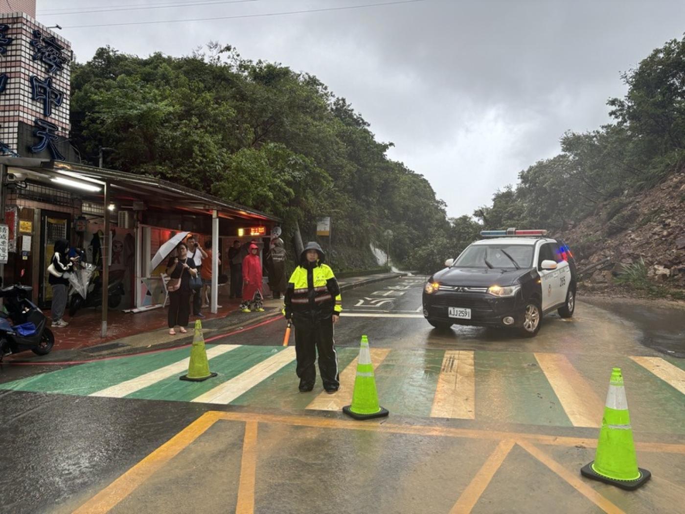 基隆市新豐街4日凌晨因大雨造成海中天社區前山坡有大面積土石崩落走山，交通中斷，警方獲報後隨即冒雨前往管制。讀者提供