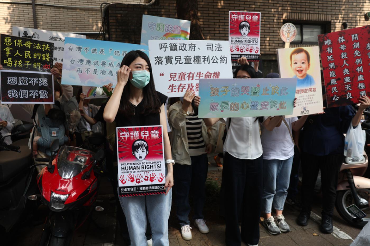 「剴剴」案宣判，關心的民眾持手板在法院前呼籲重視虐兒問題。中央社