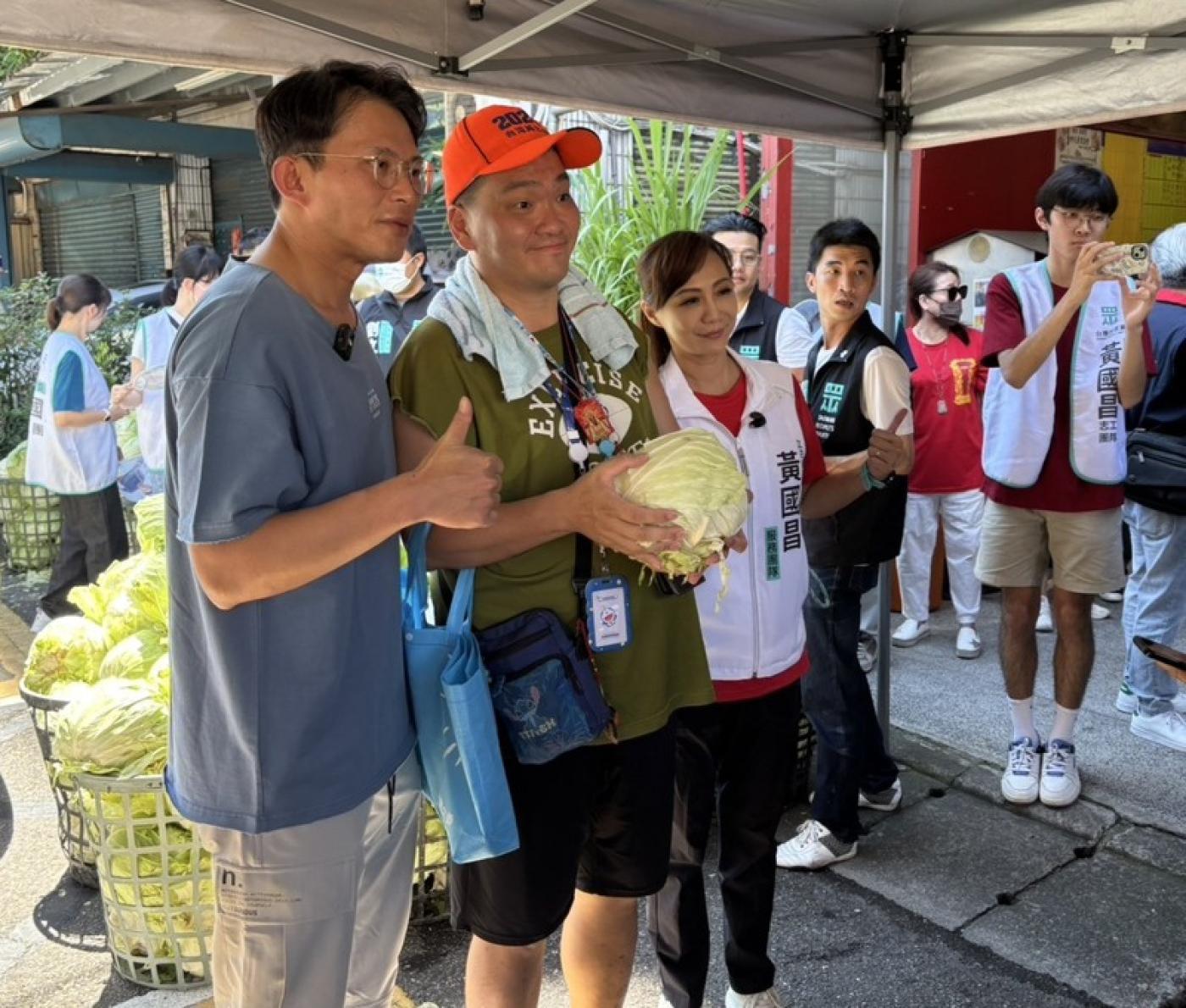 民眾黨主席黃國昌（左1）28日偕新北服務團隊前往新北市三重，並發放高麗菜給當地居民，以行動聲援高麗菜農。中央社