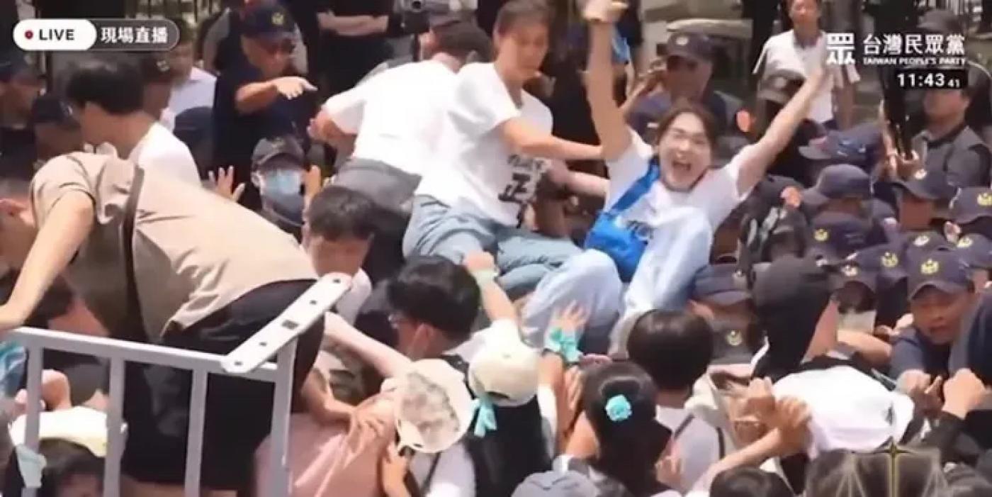 民眾黨女性支持者在同伴幫助下穿過警方人牆，成功時還做出如同演唱會慶賀時在人群上「衝浪」的反應。翻攝民眾之聲