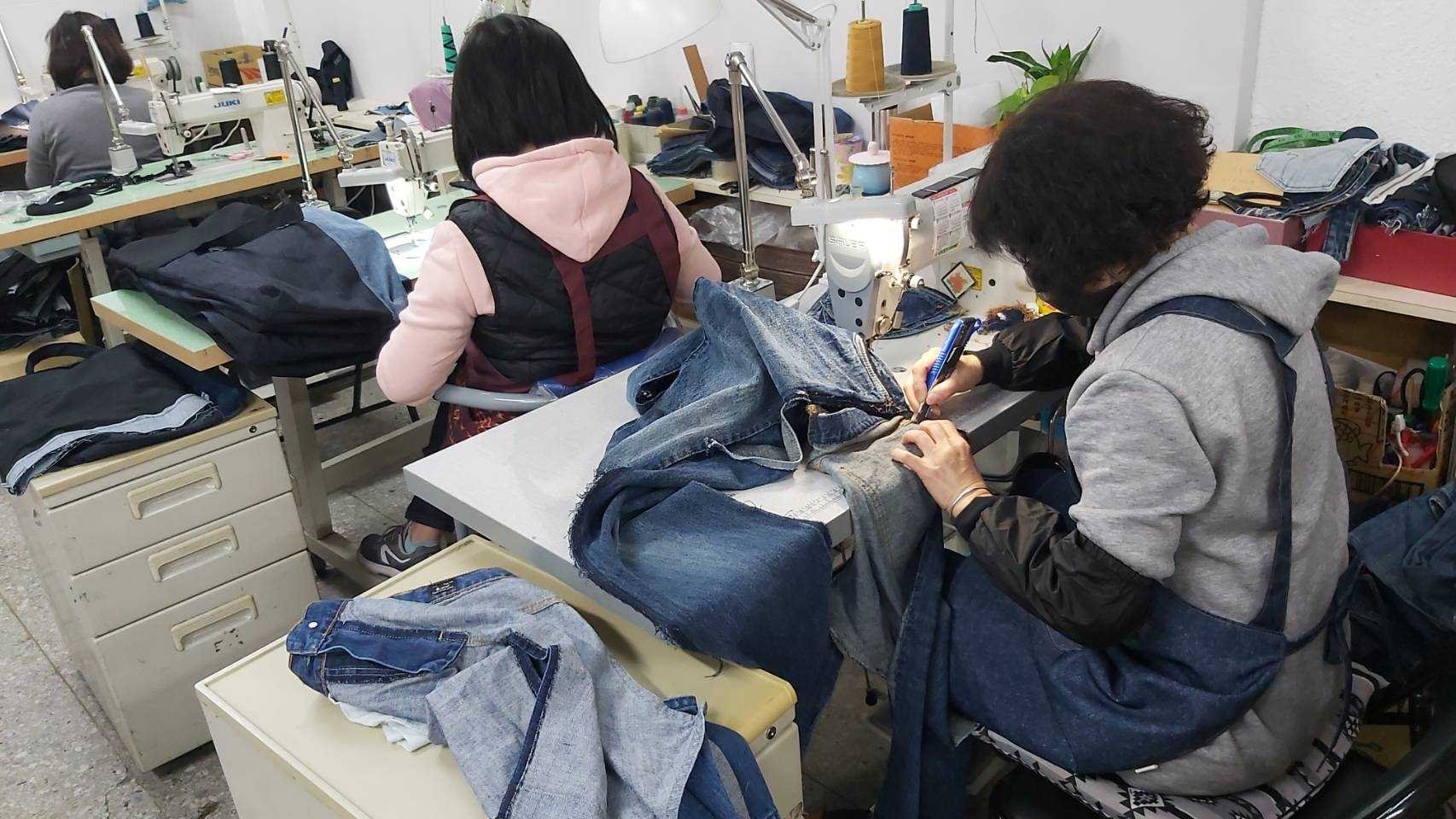 新知工坊的婦女使用美工刀，細心拆解回收的牛仔褲。新知工坊提供